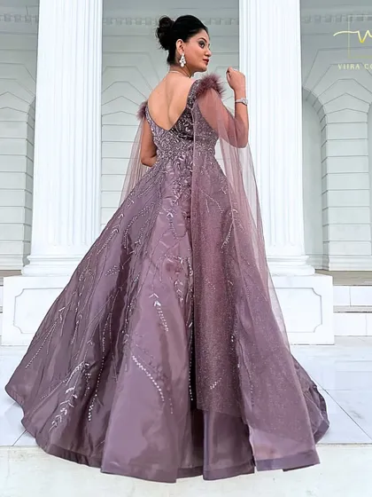 A back three-quarter view of the mauve gown, highlighting the flowing cape sleeves.