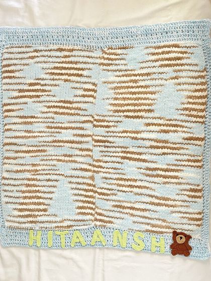 A full, flat view of the knitted blanket for "Hitaansh." The knitting process for this yarn takes more time and effort, but it creates a uniquely soft and durable baby blanket.