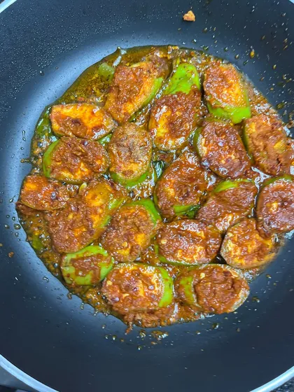 An overhead shot of the raw banana roast in the pan. The slices are perfectly arranged, ensuring each one gets evenly coated in the spicy, umami-rich masala.