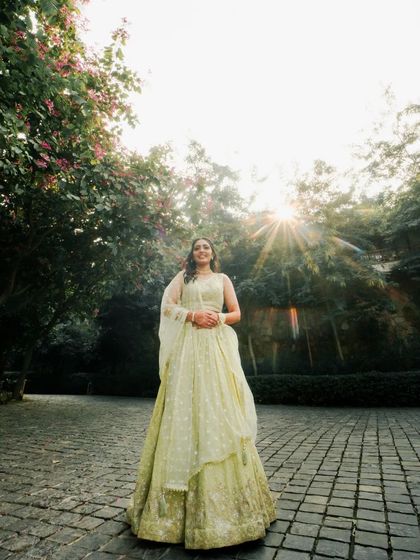 A sun-drenched portrait of the bride in her Mehendi outfit, the light creating a beautiful flare behind her.