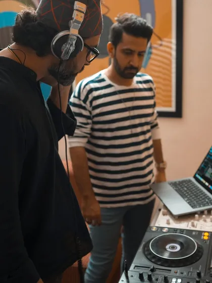 During a DJ training session, I focus on the details. Here, I'm working closely with a student, observing his technique on the decks and providing immediate feedback to help him refine his mixing skills.