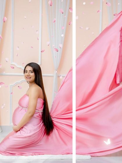 A classic kneeling pose in a beautiful pink satin gown. The flowing fabric and falling petals create a soft, romantic, and feminine atmosphere.