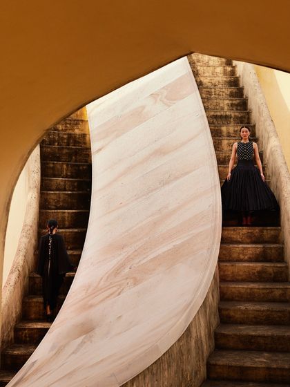 A dramatic shot on the steps of the observatory. The composition uses the curves of the architecture to frame the two models.