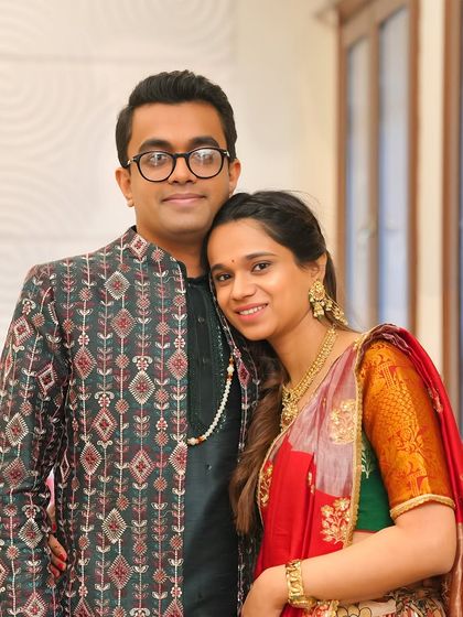 A happy couple posing together. The groom's Indo-Western jacket with its high-rise neck and traditional pattern perfectly complements the bride's classic attire.