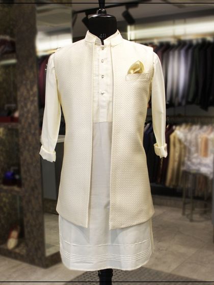 An elegant off-white kurta paired with a matching textured Nehru jacket. This classic, monochromatic look is perfect for a daytime event or a puja ceremony.