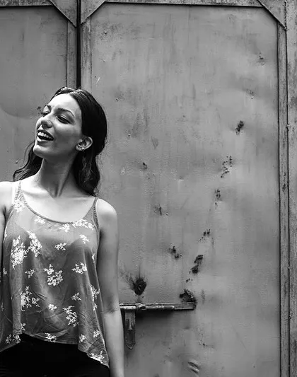 A woman with a fan against a rustic, textured background. This black and white portrait has a timeless, classic feel.