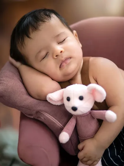 An intimate close-up capturing the peaceful expression of the sleeping baby, his soft cheek resting against the miniature sofa.