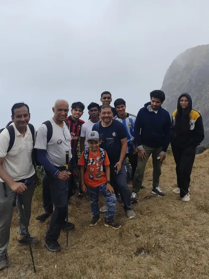 A family and friends group posing on the trail, with the misty peaks of Kumara Parvatha in the background.