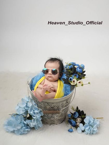 This little one is already a star. A fun and quirky shot of a newborn wearing sunglasses while relaxing in a bucket, showing that baby photoshoots can have a playful side.