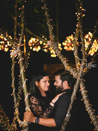 A close-up, intimate portrait of a couple among the fairy-lit trees.