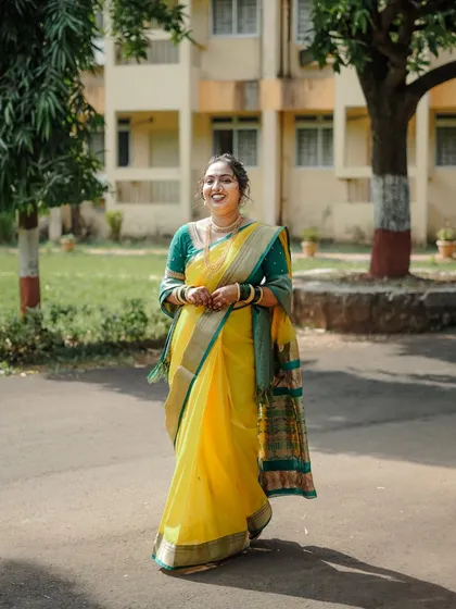 A full-length shot of a bride in a bright yellow saree, walking and smiling. This candid style captures the happiness of the day.
