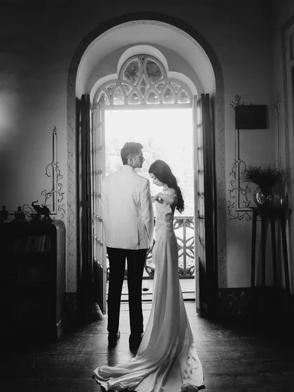 A timeless black and white portrait of Sahil and Khushali, framed by a grand archway. I use dramatic light and shadow to create cinematic moments that feel both modern and eternal.
