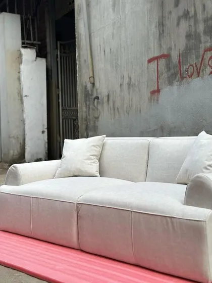A full view of the minimalist white sofa, showcasing its deep seats and clean, blocky form.
