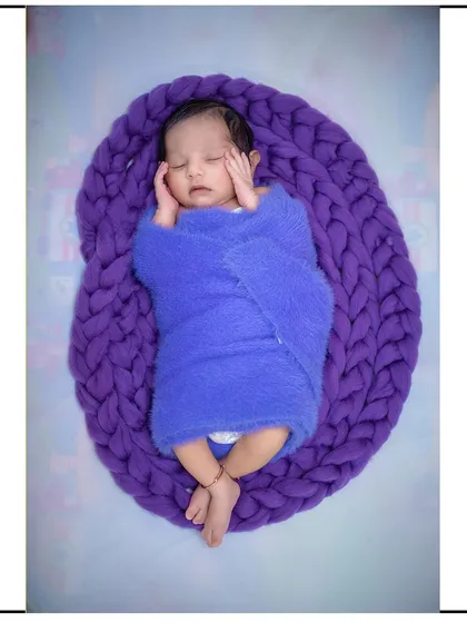 A cozy and safe newborn pose. This baby is comfortably nestled in a chunky knit basket, a popular prop I provide for my newborn studio sessions.