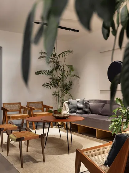 The living area of our 'Rustic Minimal' apartment project in Bangalore, designed for a young couple. We used a neutral palette of cement floors and mahogany wood furniture to create a warm, gallery-like feel. This space is filled with natural light and indoor plants, reflecting our love for biophilic design that brings the calming presence of nature indoors.