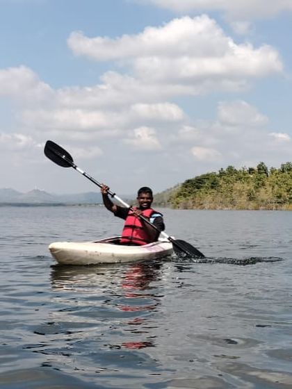 A smiling participant enjoys a solo kayaking session on a beautiful day at Vani Vilas Sagar.