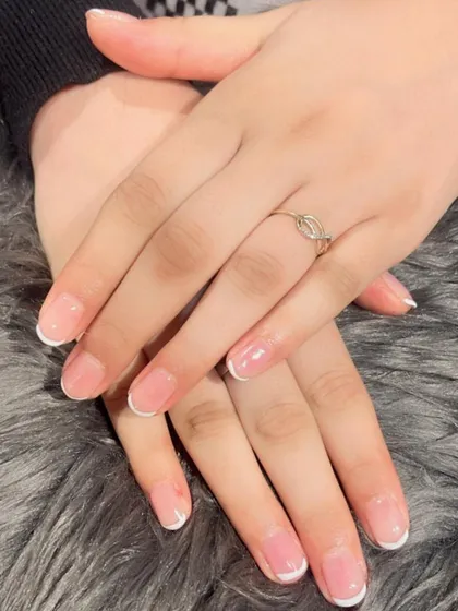 A delicate and subtle French manicure on shorter, natural-looking nails. This is my go-to recommendation for everyday elegance.
