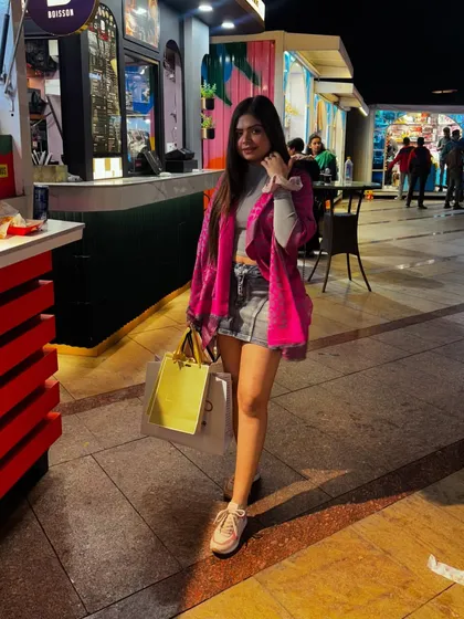 A casual shopping day outfit with a grey crop top, denim skirt, and a pink shawl.