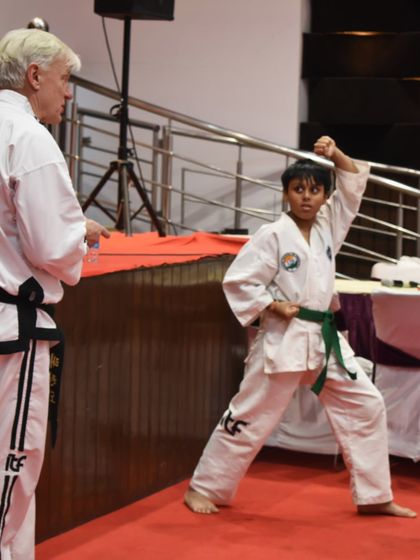 A student performs a pattern under the watchful eye of a Grandmaster during a technical seminar.