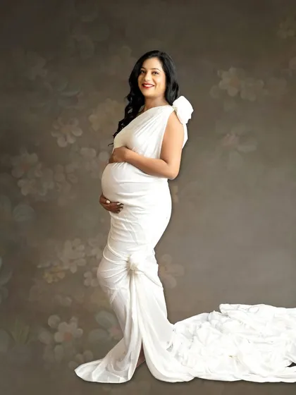 A classic fine-art portrait using a single white drape styled as a Grecian gown. The floral textured background adds a soft, romantic feel.