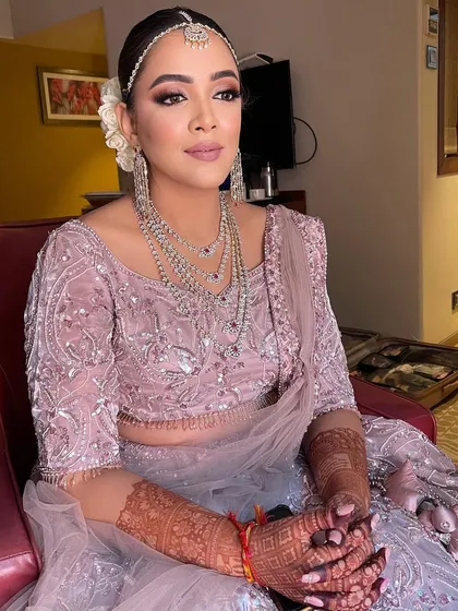 A sleek and clean bridal bun adorned with white roses and a matha patti. This hairstyle creates a very royal and polished look for the wedding day.