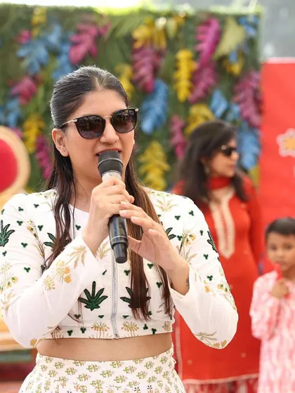 A close up of me on the mic, with the colorful Haldi decor in the background. I am focused and ready to bring the energy.
