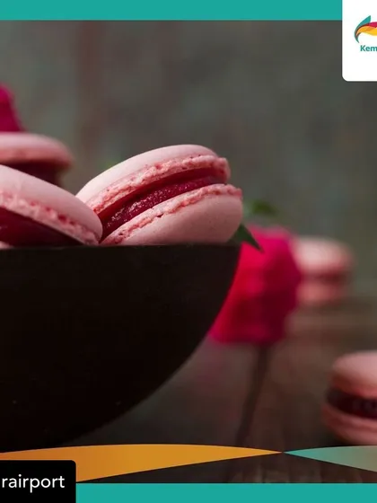 A close-up of our vibrant pink macarons, filled with a rich fruit compote. This shot, taken at our airport kiosk, highlights the beauty and craft of our patisserie.