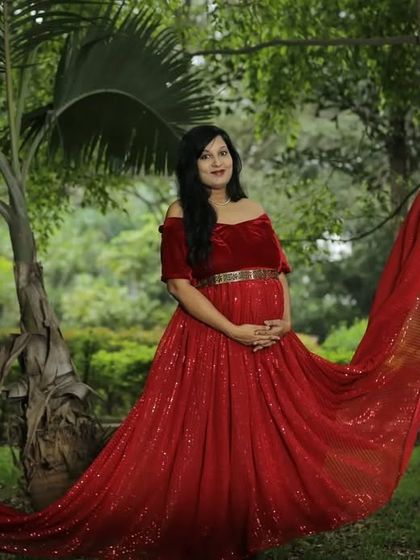 The sparkling fabric of this red sequin flying gown looks incredible in the sunlight. It's a glamorous choice for an outdoor maternity session.