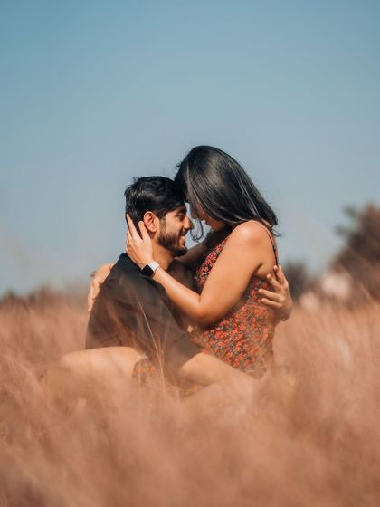 An intimate embrace in a sunlit field, focusing on the couple's close connection. We use framing and natural light to create a dreamy, cinematic quality in our photos.