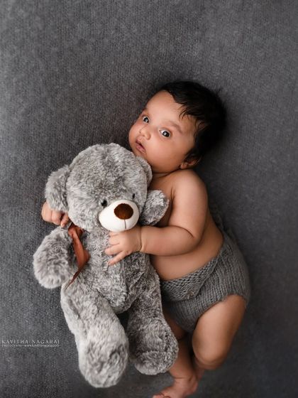 A one-month-old baby boy cuddles his teddy bear, giving the camera a very serious look. A fun and personal way to document this stage.