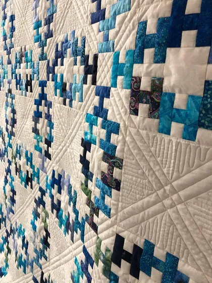 A close-up of the beautiful Summer Wedding Ring quilt, showing the ruler work and echo quilting.
