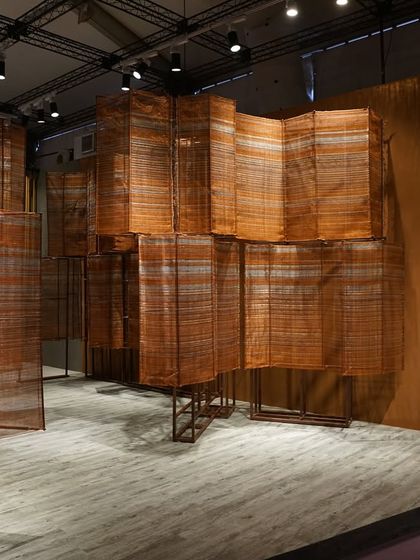 The 'India Everywhere' installation, where monumental woven copper screens create an architectural experience. The text on the wall provides context for the narrative of India's modern aspirations and rich history.