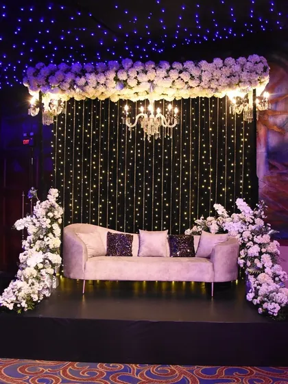 A cozy and romantic seating area for a Sangeet, with a plush sofa set against a backdrop of fairy lights, creating the illusion of a starry night sky.