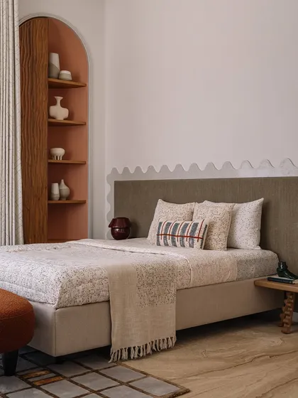 The guest bedroom at Rehethaan is a cozy oasis. A terracotta-coloured arched niche provides a home for books, while a custom terrazzo architrave with a wavy profile adds a dash of whimsy to the room.