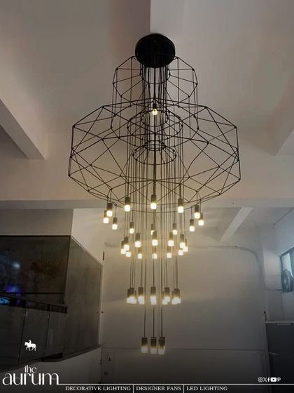 This custom-designed geometric chandelier is functional art. Its complex, wireframe structure and cascading bulbs create a stunning visual centerpiece in a modern, industrial-style loft or commercial space.