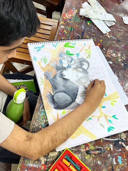 A young artist deeply focused on his koala drawing. Our classes help kids develop patience and attention to detail, seeing a project through from sketch to finished piece.