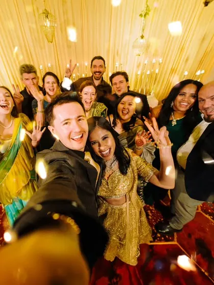 A high-energy selfie taken by the groom, capturing the happy faces of all their friends and family on the dance floor.