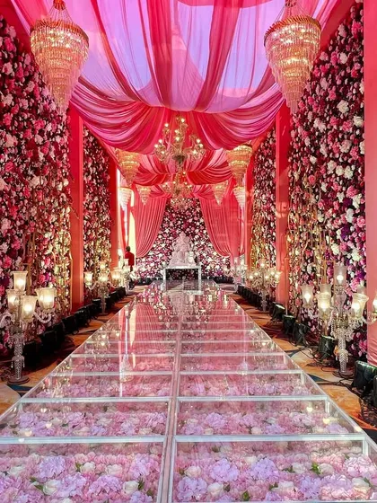 A truly one-of-a-kind aisle for a modern fairytale wedding. This stunning glass walkway filled with pink hydrangeas, surrounded by walls of flowers and grand chandeliers, shows how we can turn an ambitious idea into a breathtaking reality.