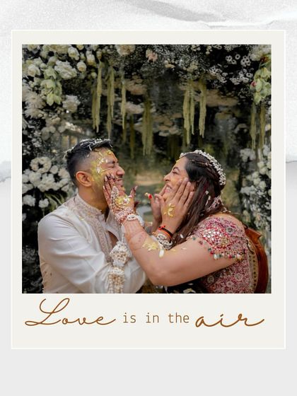 A polaroid-style shot capturing a playful moment from the Haldi ceremony, with the couple surrounded by a canopy of white and green florals.