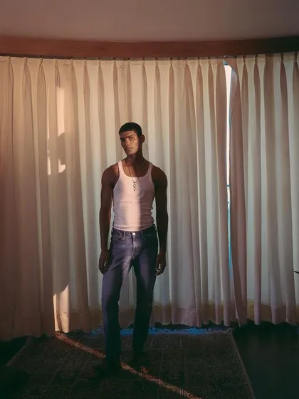 A wide shot for an Amama Jewels campaign, featured on PhotoVogue. The image uses natural light filtering through curtains to create a soft, cinematic mood.