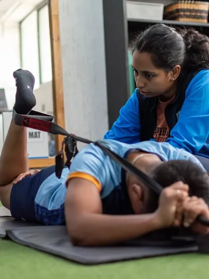 Here, a physiotherapist works with an athlete on a hamstring stretch. This hands-on approach ensures proper form and helps clients safely increase their flexibility and range of motion post-injury.