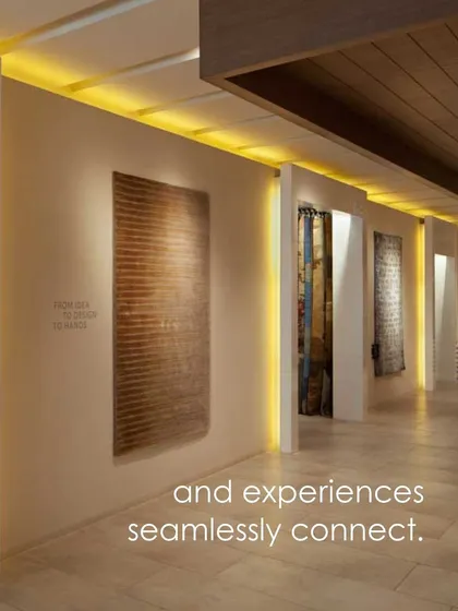 A view of the Hands Carpets showroom where lighting is used to highlight the texture and artistry of a wall-hung carpet. The space is designed as a gallery, where each piece tells a story.