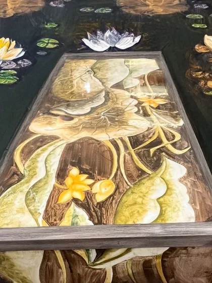 An artistic shot of our hand-painted lotus table, appearing to float on water. This image captures the serene and timeless elegance that inspired its design.