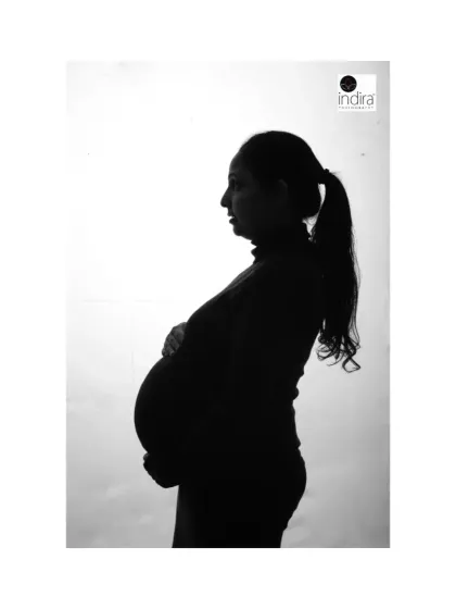 This silhouette shot features the mother-to-be with her hair in a ponytail, creating a clean and modern outline against the bright background.