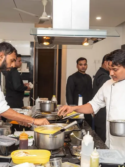 A busy moment on the line, with our chefs working together to plate dishes during a high-volume catering service. The organized chaos of a professional kitchen.