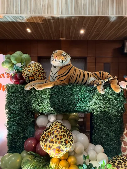 A close up of the details in our jungle theme decor, featuring a realistic tiger prop resting on a faux hedge. These elements make the theme more immersive and fun for kids.