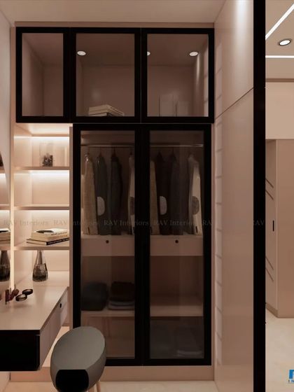 A view of a walk-in closet with a vanity, featuring glass-fronted wardrobes and well-lit shelves.
