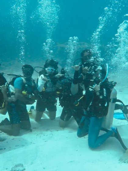 A group of newly certified divers celebrating their achievement underwater. This is the moment all the training pays off.