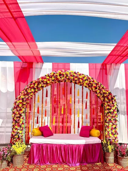 Bright, bold, and beautiful. This Mehandi seating area combined vibrant pink and white drapes with a stunning floral arch and colorful tassels, creating a picture-perfect spot for the bride.