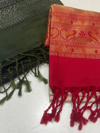 A pairing of contrasting styles. This image shows an olive green saree with a subtle silver pattern next to a vibrant red saree with a traditional bird motif border.